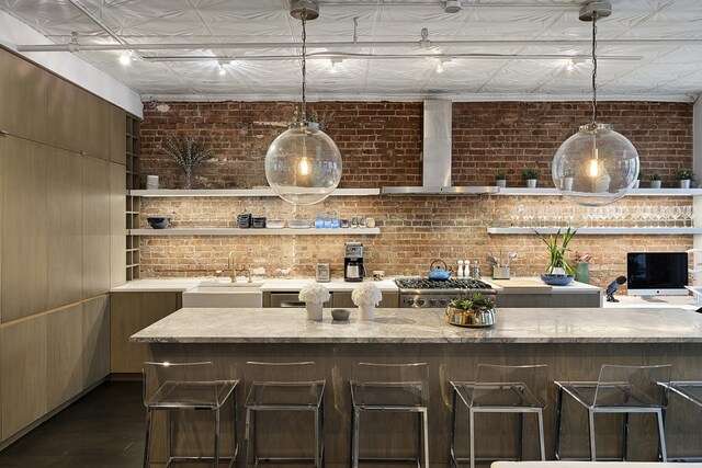 bar featuring a sink, an ornate ceiling, brick wall, and wall chimney exhaust hood