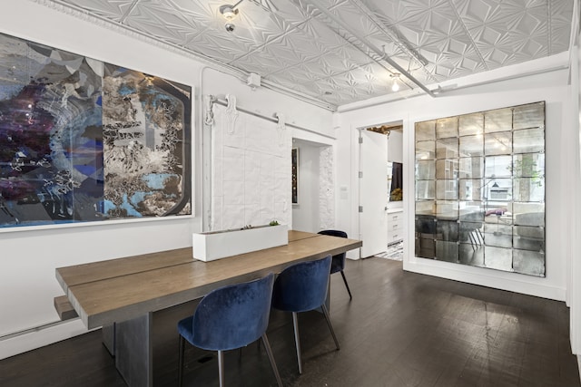 dining area featuring baseboard heating, an ornate ceiling, a barn door, and wood finished floors