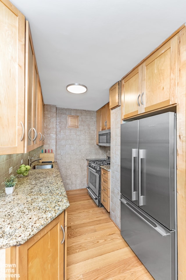 155 E 38th St Unit 16B, New York City, NY 10016 - kitchen featuring stainless steel appliances, a sink, light wood finished floors, and backsplash