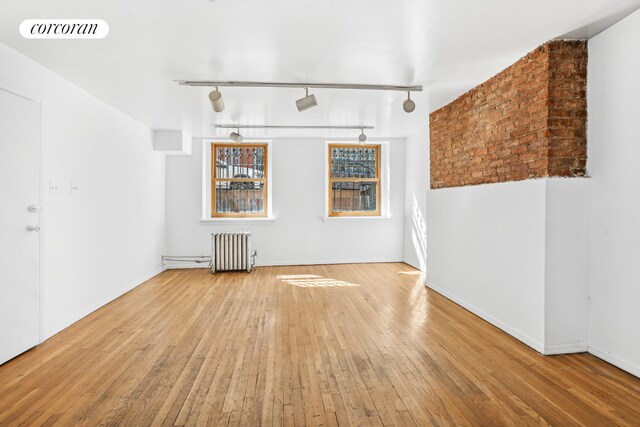 43 Charlton St, New York City, NY 10014 - unfurnished room featuring radiator heating unit, hardwood / wood-style flooring, track lighting, baseboards, and visible vents