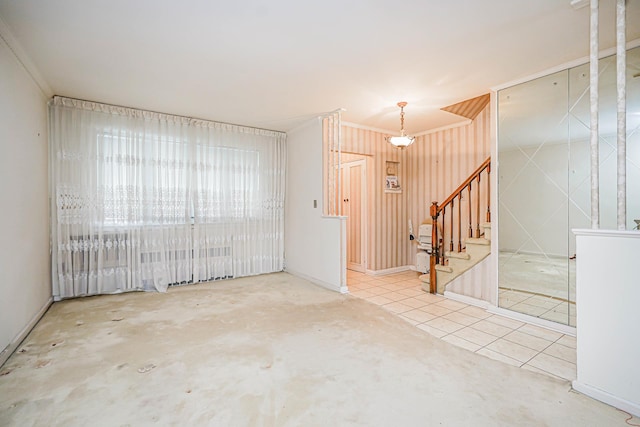 spare room with stairs, crown molding, and tile patterned floors