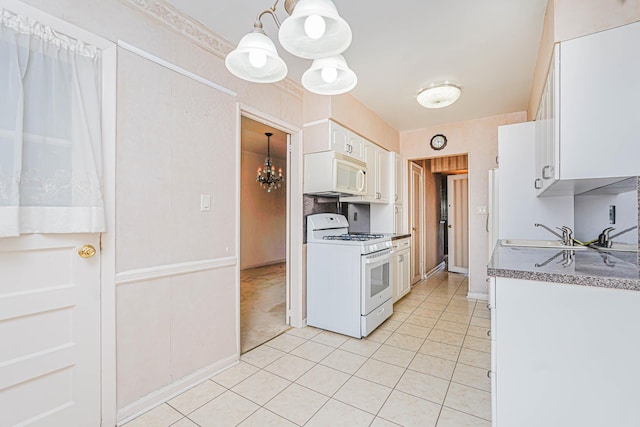 kitchen with white appliances, a chandelier, light tile patterned floors, a sink, and white cabinetry