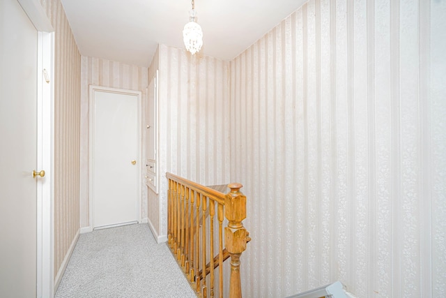 corridor featuring wallpapered walls, an upstairs landing, carpet, and baseboards