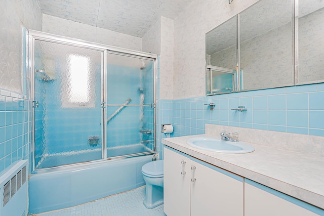 full bath featuring radiator heating unit, tile walls, vanity, shower / bath combination with glass door, and tile patterned floors