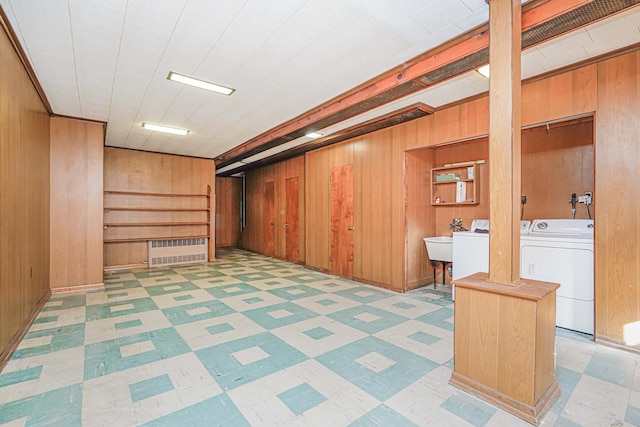 finished below grade area with tile patterned floors, independent washer and dryer, wooden walls, and a sink