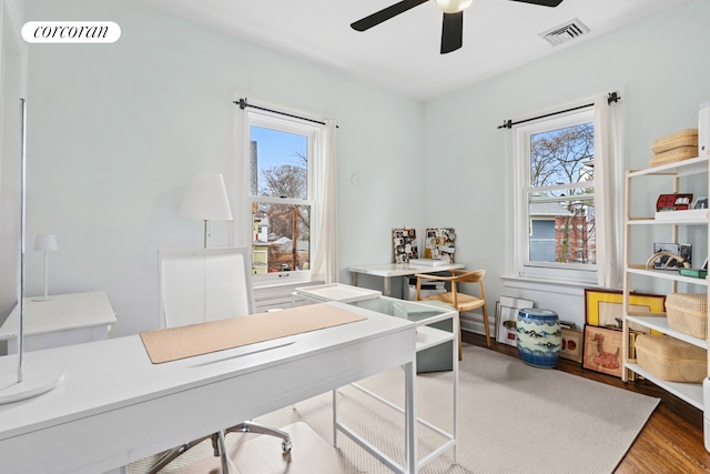home office featuring a wealth of natural light, ceiling fan, wood finished floors, and visible vents
