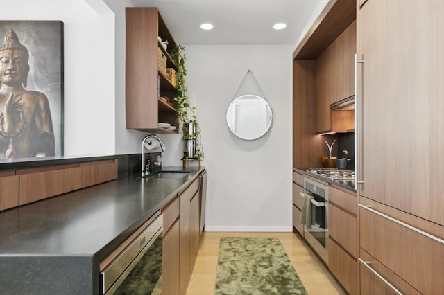 kitchen featuring stainless steel appliances, open shelves, dark countertops, modern cabinets, and a sink