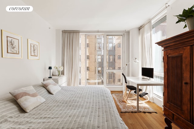 bedroom featuring wood finished floors and floor to ceiling windows