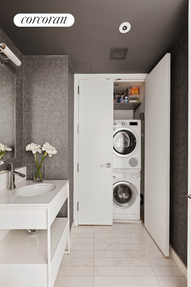 clothes washing area with stacked washer and clothes dryer and tile patterned floors