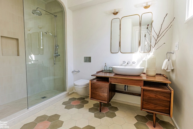 full bathroom featuring vanity, toilet, tile patterned flooring, and tiled shower