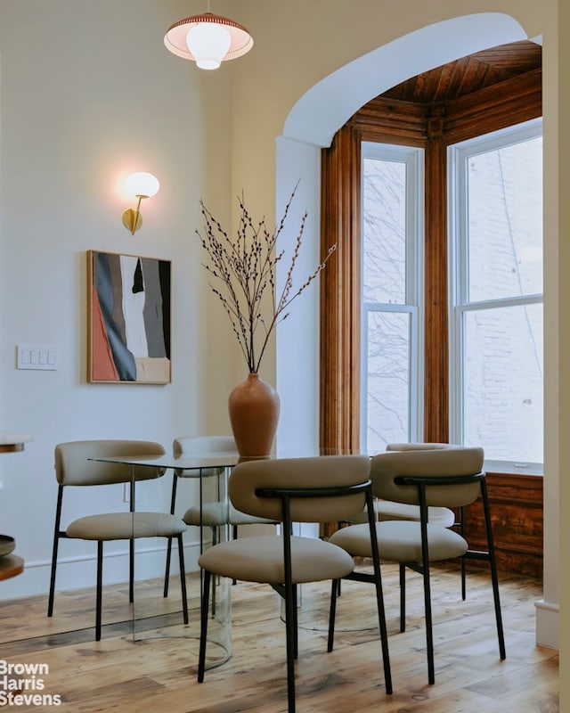dining area with arched walkways and wood finished floors