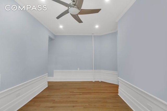 spare room with crown molding, a ceiling fan, light wood-style flooring, recessed lighting, and wainscoting