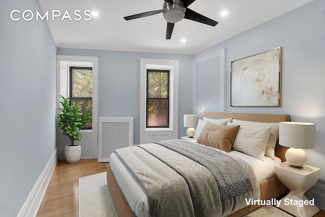 bedroom with radiator, multiple windows, light wood-style floors, baseboards, and recessed lighting