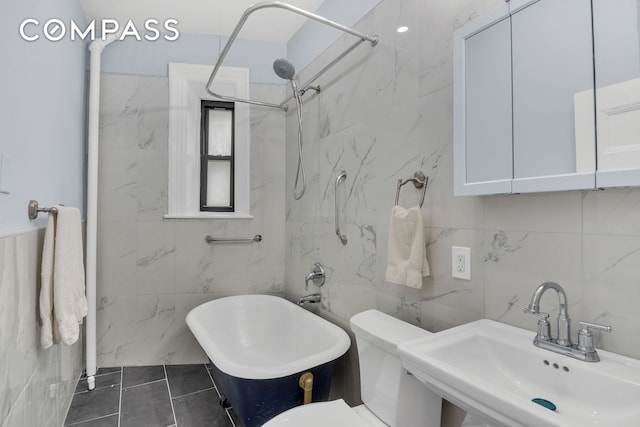 full bathroom with tile walls, a sink, a freestanding tub, a shower, and toilet