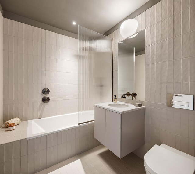 144 Vanderbilt Ave Unit 2C, New York City, NY 11205 - bathroom featuring tile walls, vanity, tile patterned flooring, tiled shower / bath combo, and toilet