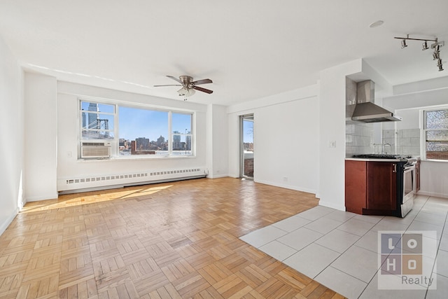 unfurnished living room with a ceiling fan, baseboards, a healthy amount of sunlight, and baseboard heating