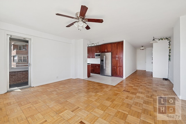 unfurnished living room featuring a ceiling fan and baseboards