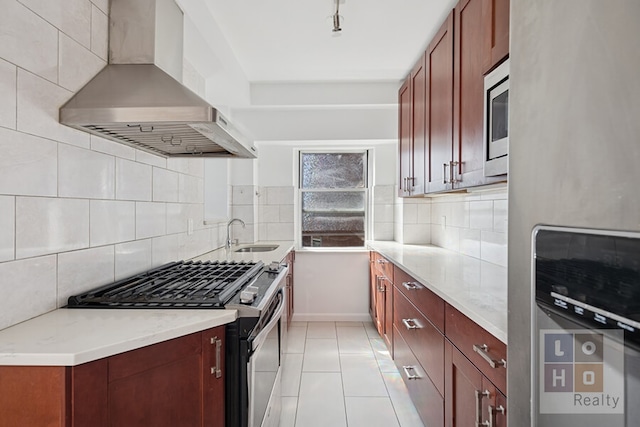kitchen featuring wall chimney exhaust hood, a sink, backsplash, light tile patterned floors, and stainless steel appliances