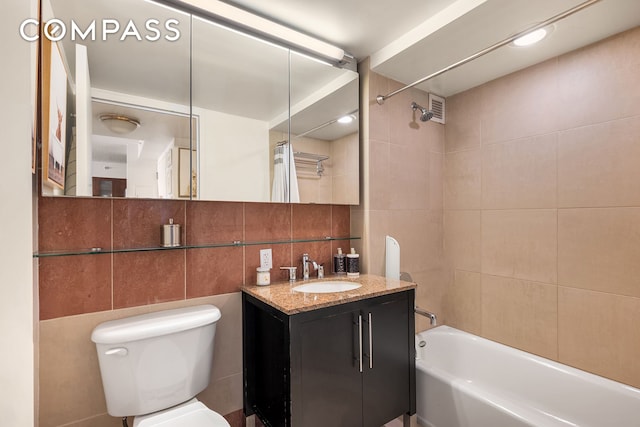 full bathroom with tub / shower combination, tile walls, toilet, and vanity