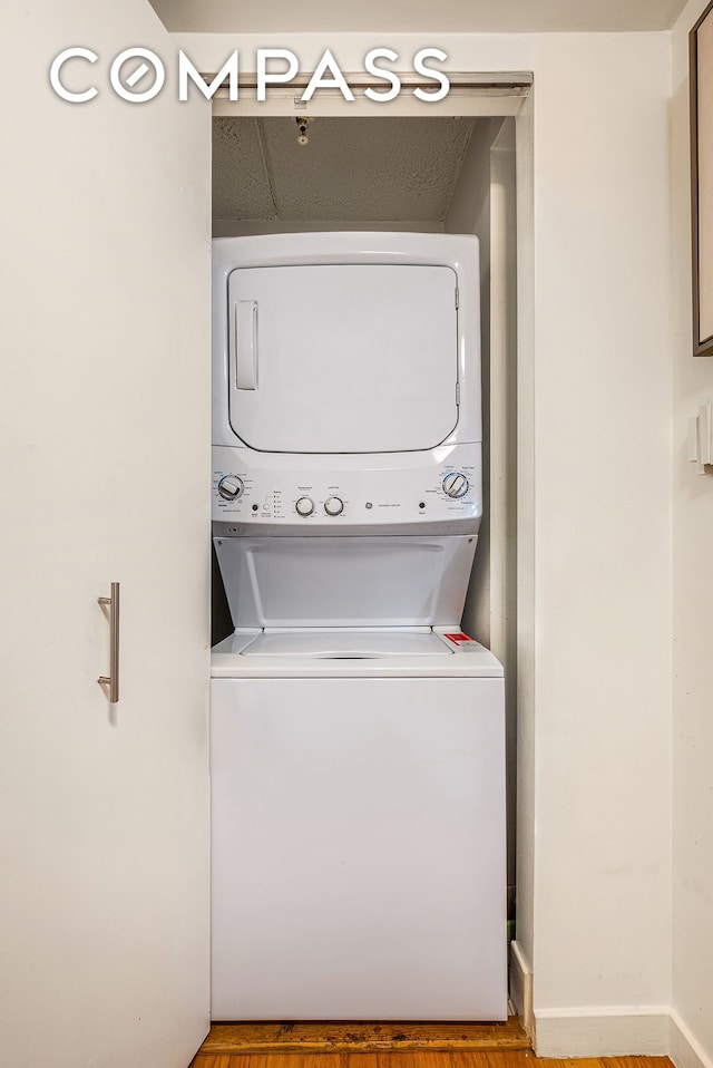 washroom with stacked washer and clothes dryer and wood finished floors