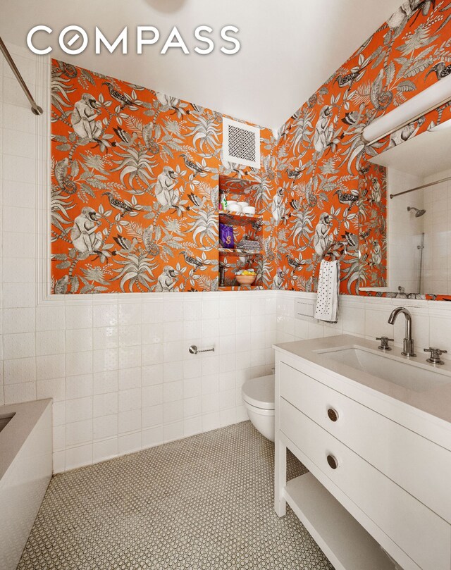 309 W 86th St Ph, Ph, New York City, NY 10024 - bathroom featuring wallpapered walls, tile walls, vanity, toilet, and wainscoting