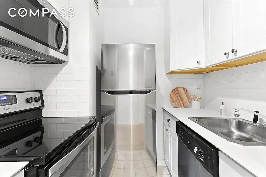 343 E 74th St Unit 7D, New York City, NY 10021 - kitchen featuring stainless steel appliances, white cabinets, tasteful backsplash, light tile patterned floors, and light countertops