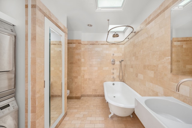 1342 Lexington Ave, New York City, NY 10128 - bathroom featuring tile walls, estacked washer and dryer, a tile shower, a soaking tub, and tile patterned floors
