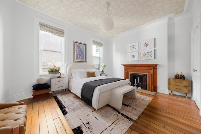 1342 Lexington Ave, New York City, NY 10128 - bedroom featuring light wood-type flooring, an ornate ceiling, crown molding, a fireplace with raised hearth, and baseboards