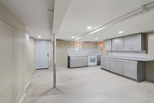 30-53 23rd St, New York City, NY 11102 - kitchen featuring white range with gas cooktop, gray cabinets, recessed lighting, decorative backsplash, and light countertops