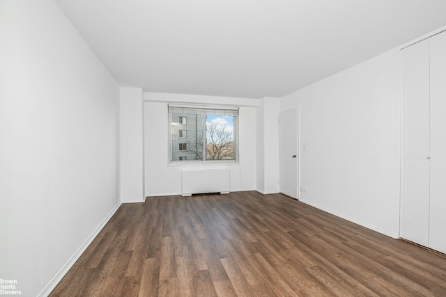 spare room featuring baseboards and wood finished floors