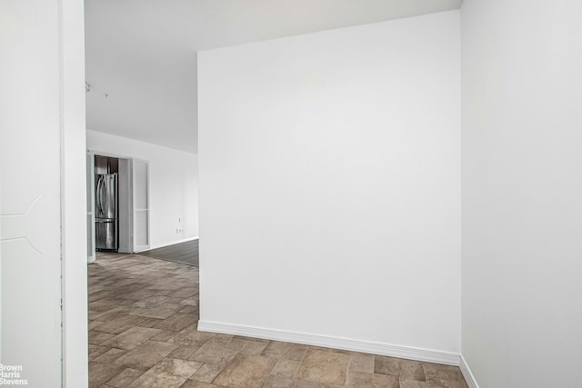 spare room featuring baseboards and stone finish floor