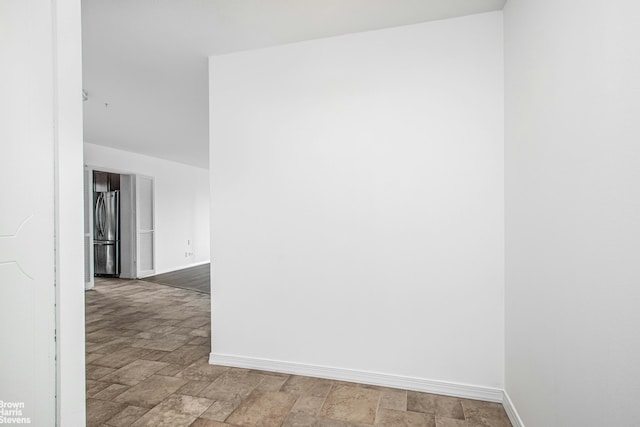 spare room featuring baseboards and stone finish floor