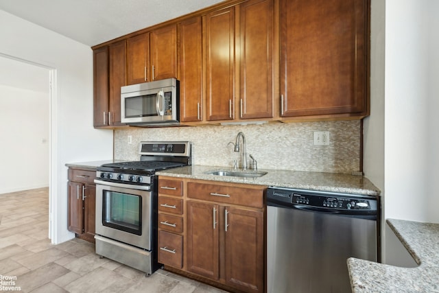 kitchen with a sink, tasteful backsplash, light stone countertops, and stainless steel appliances