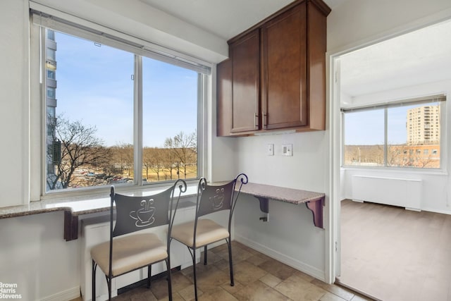 dining space featuring baseboards, stone finish flooring, and radiator heating unit