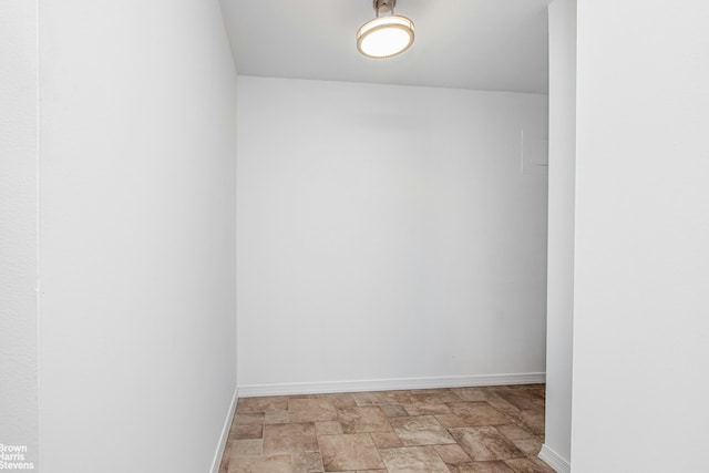 unfurnished room with baseboards and stone finish flooring