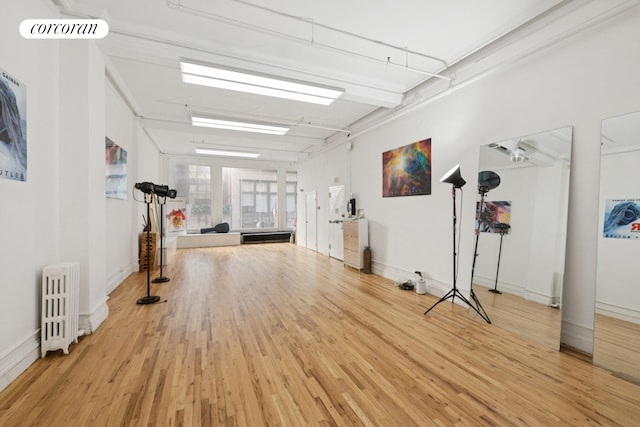workout area with radiator, wood finished floors, and baseboards