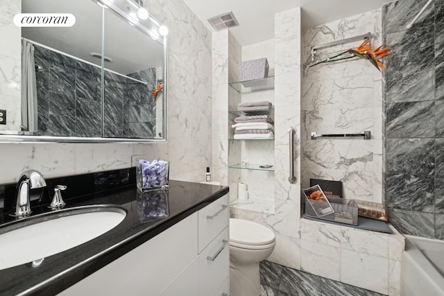 bathroom with marble tiled floors, a shower with shower door, vanity, a tub to relax in, and toilet
