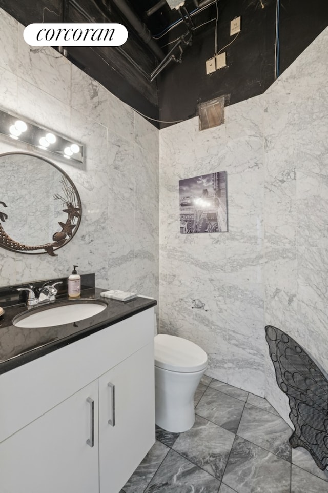 half bathroom with tile walls, vanity, and toilet