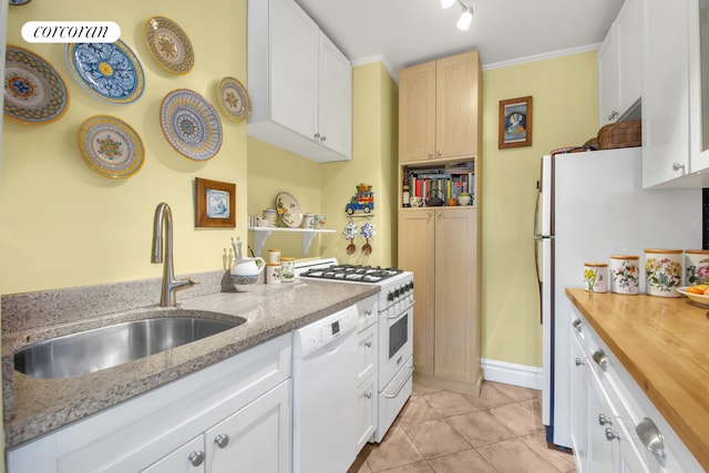 kitchen with a sink, light tile patterned floors, white cabinets, butcher block counters, and white appliances