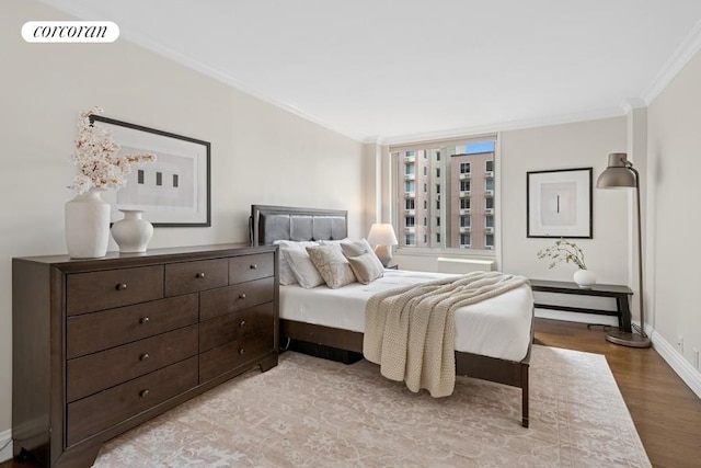bedroom with light wood-style floors, crown molding, and baseboards