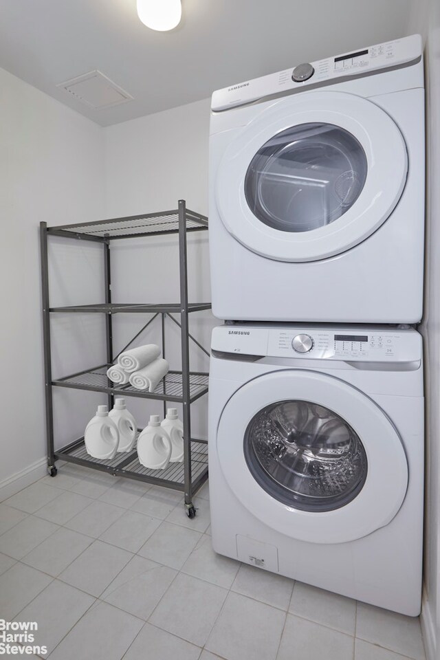 washroom with light tile patterned floors, baseboards, laundry area, and stacked washer and dryer