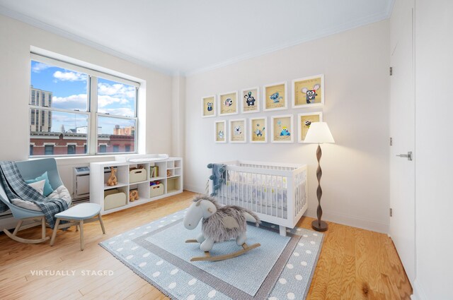 1787 Madison Ave Unit 402, New York City, NY 10035 - bedroom featuring wood finished floors, ornamental molding, baseboards, and a nursery area