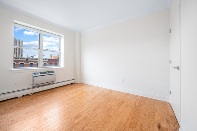 spare room with a baseboard heating unit, light wood-type flooring, crown molding, and baseboards