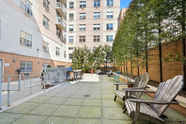 view of community featuring fence, outdoor dining space, and a patio