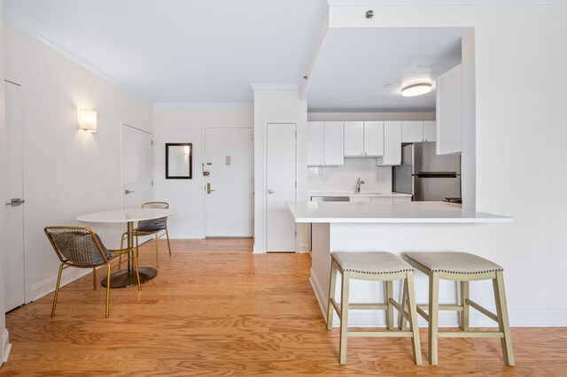 1787 Madison Ave Unit 402, New York City, NY 10035 - kitchen with freestanding refrigerator, a sink, light countertops, a kitchen bar, and white cabinets