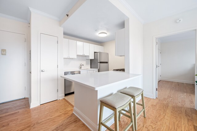 1787 Madison Ave Unit 402, New York City, NY 10035 - kitchen featuring appliances with stainless steel finishes, a kitchen bar, a sink, light wood finished floors, and light countertops