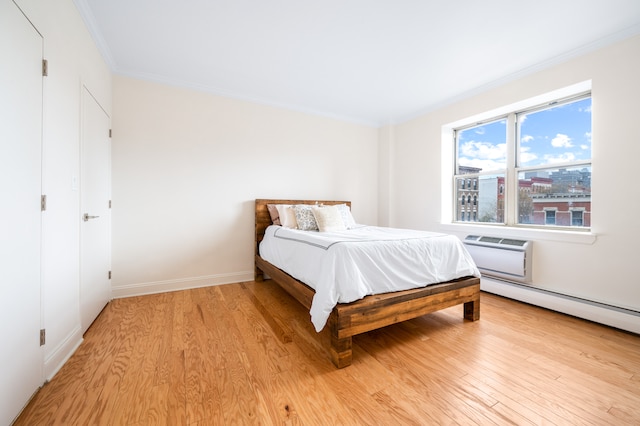 bedroom featuring light wood finished floors, baseboards, a wall mounted AC, and ornamental molding