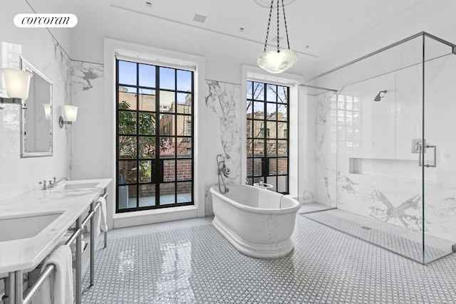 bathroom with a freestanding bath, a sink, a marble finish shower, and double vanity