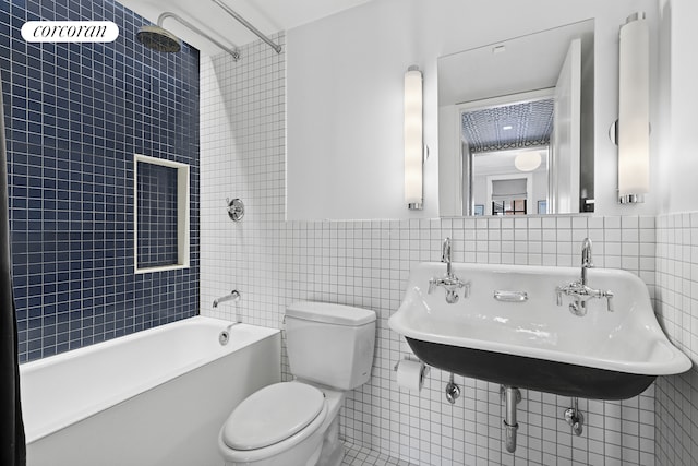 bathroom with toilet, a sink, tub / shower combination, and tile walls