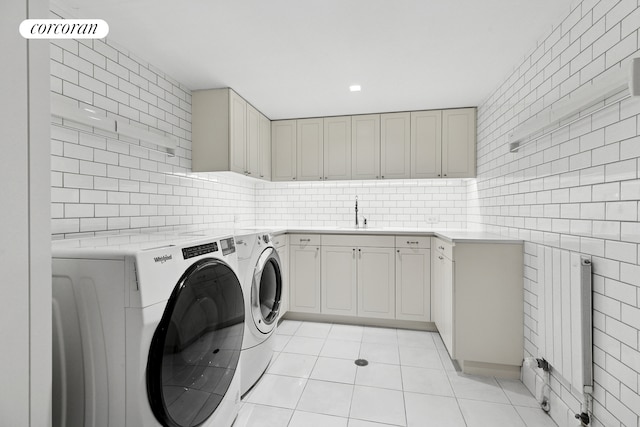 laundry area with a sink, tile walls, light tile patterned floors, cabinet space, and washing machine and dryer